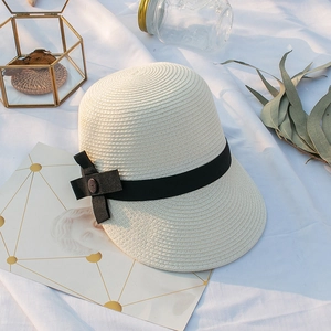 Détail d'un chapeau de soleil en paille avec un ruban noir et un bouton vintage chic