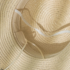 Detail view of woven straw hat interior with sweatband, chin strap and adjustment string