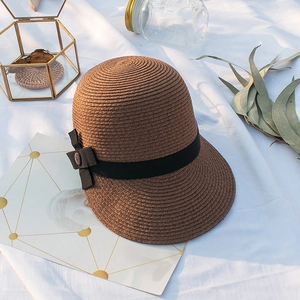 Détail d'un chapeau de paille marron tissé à la main avec ruban noir et bouton décoratif