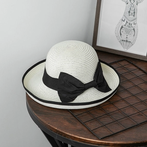 Dettaglio della fine trama di paglia e del fiocco nero su un cappello da sole bianco
