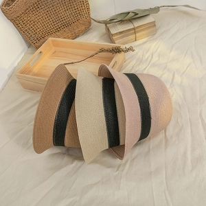Close-up of summer straw bucket hats in brown, beige and pink with woven stripe details