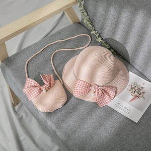 Detail of pink straw hat and crossbody bag with plaid bows and pearl accents