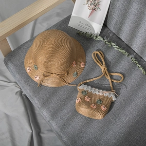 Detail of girls' brown straw hat and matching crossbody bag with lace and daisies