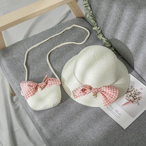 Detail view of a straw hat and matching bag with pink bows and pearl charms for girls
