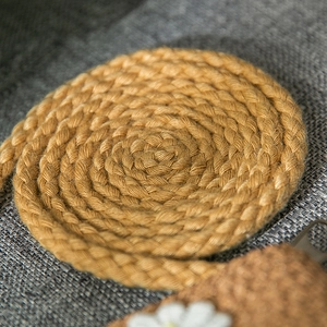 Close-up of golden brown woven rope strap with small white flower details on a straw bag