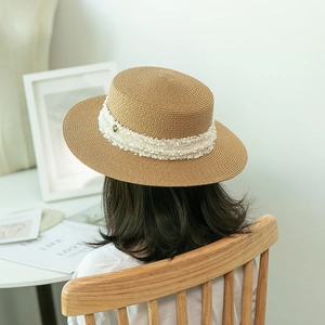 Back view of a summer straw boater hat with white fringe ribbon and gold M metal letter