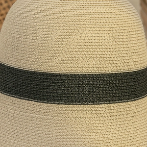 Close-up detail of high-density straw weave texture and black ribbon on sun hat