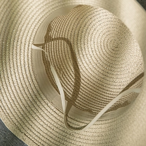 Detail of the woven straw hat interior featuring a beige sweatband and elastic chin strap