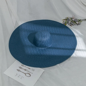 Detail of dark blue wide brim straw hat with fine weave texture on white checkered fabric
