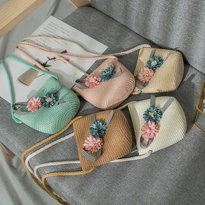 Detail view of colorful woven straw bags for girls with 3D floral accents and ribbon
