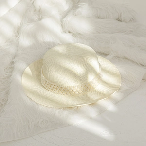 Detailed macro view of the boater hat showing woven texture and elegant pearl band decoration