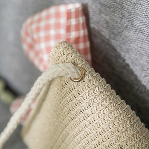 Close-up of tight straw weave texture on girls sun bag with metal eyelets and rope strap