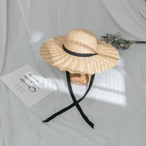 Summer wide brim straw sun hat with wavy edges and black ribbon ties for beach vacation