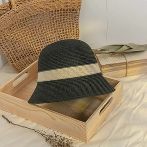 Japanese style black woven straw sun hat with beige ribbon trim on vintage background