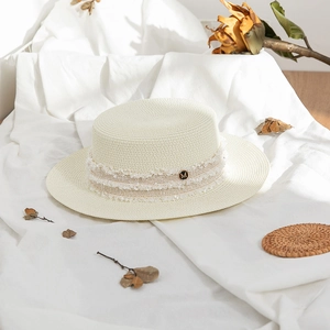Detail of French straw hat with frayed ribbon and vintage gold letter M emblem