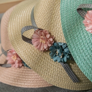 Detail of woven straw hats featuring 3D fabric flowers and polka dot ribbon accents