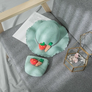 Détail d'un ensemble chapeau de paille et sac vert menthe avec ornements de fruits