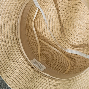 Detail view of woven straw hat interior with sweatband, elastic chin strap and size label