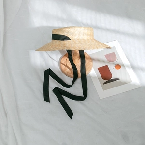 Détail d'un chapeau de paille de type canotier avec ruban noir sur support