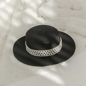 Detail showing elegant pearl mesh band decoration on black straw flat top hat for beach