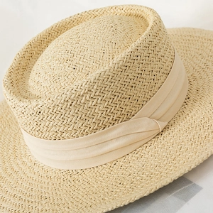 Detailed close-up of woven straw texture and elegant satin ribbon on a flat top sun hat