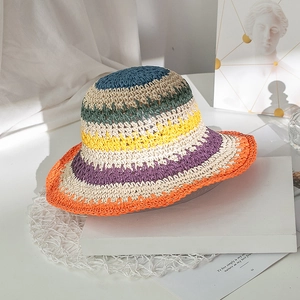 Dettaglio cappello di paglia intrecciato a mano con strisce colorate e tesa arancione