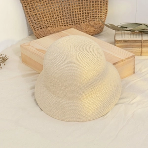 Detail of minimalist beige woven straw bucket hat on a wooden block with vintage decor