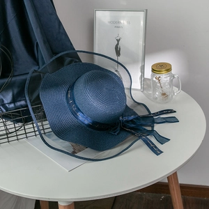 Detail of navy blue straw sun hat featuring a sheer organza brim and inscribed bow ribbon