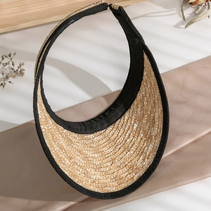 Detailed close-up of handmade straw visor with black fabric trim on silk background