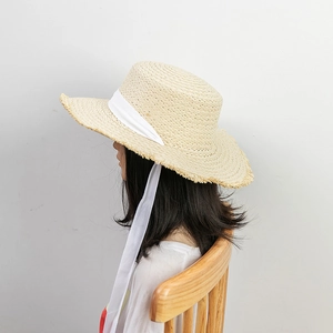 Women's straw sun hat with frayed brim and white bow tie ribbon for beach summer wear