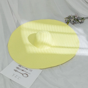Detail shot of bright yellow wide-brim straw hat on white fabric with holiday decor
