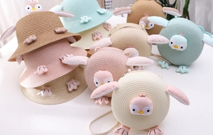 Detailed view of woven straw sun hats and bags set with 3D cartoon penguin designs