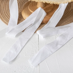 Close-up of white herringbone woven cotton ribbon texture on a natural wooden background