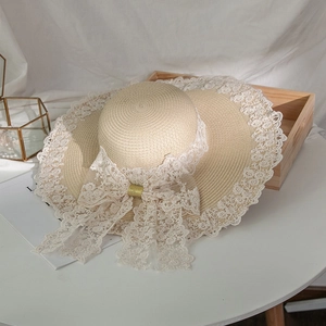 Dettaglio cappello di paglia estivo con pizzo bianco e grande fiocco decorativo