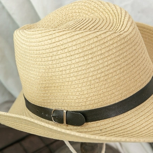 Detailed close-up of woven straw hat texture with black faux leather strap and buckle