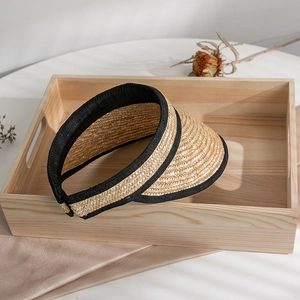 Detail of straw woven visor with black fabric trim on an elegant summer setting