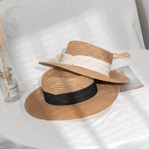 Detail of hand-woven straw boater hats with chic black and cream ribbon bands