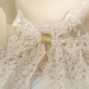 Dettaglio del fiocco in pizzo floreale con glitter dorati su cappello di paglia