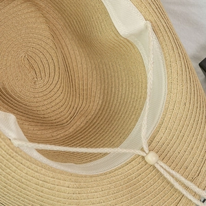 Detail of straw hat interior with adjustable chin strap and woven sweatband texture