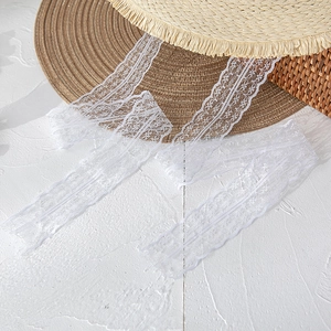 Close-up of white floral lace ribbon detail on a flat top straw sun hat for women