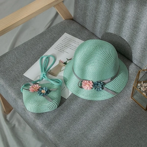 Detail of light green straw sun hat and matching floral bag set for young girls' beach trips