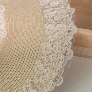 Dettaglio ravvicinato di un cappello di paglia Lolita con ricami in pizzo bianco e fiori