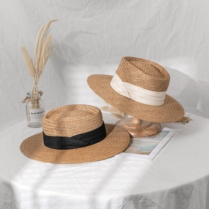 Detail of wide ribbon bows on vintage straw boater hats with fine woven texture