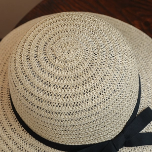 Vue détaillée d'un chapeau de soleil en paille tressée avec ruban noir élégant