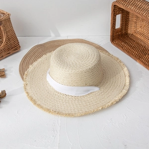 Close-up of woven straw hat with frayed edges and white ribbon detail for beach vacation
