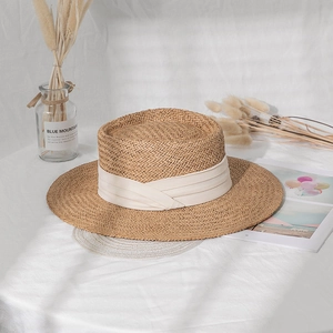 Detail of hand-woven boater hat with flat top and wide cream ribbon for sun protection