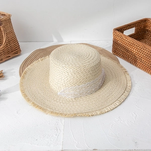 Detailed shot of straw sun hat with delicate white lace trim and frayed tassel brim edges