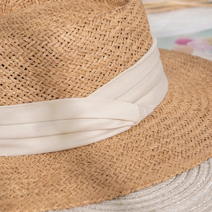 Close-up of natural straw weaving and layered beige fabric ribbon on a beach sun hat