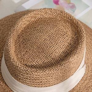 Macro shot of breathable straw sun hat with elegant beige ribbon and flat top detail
