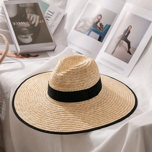 Detail of wheat straw hat with black brim binding and ribbon on white fabric